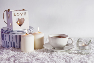 wooden white candlestick, candles, cup of tea and wooden horse on white artificial snow