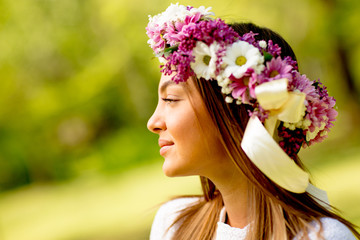Portrait of young woman with wreath of fresh flowers on head