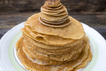 Large and small pancakes located on an old wooden table.