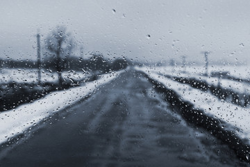 a rainy winter day, raindrops on the glass, a road going out into the distance, a black and white toned photo_