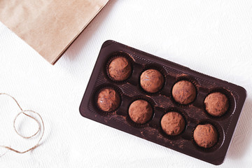 Dark cocoa truffles in the box on white background