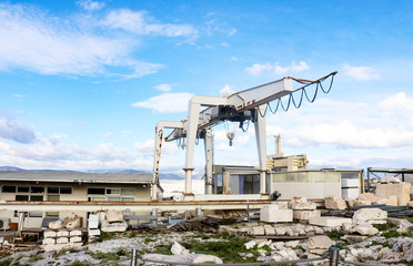 Giant crane on tracks being used to reconstruct Parthenon on Athens Acroplis with pieces of the ruins organized in foreground and Athens and mountians behind