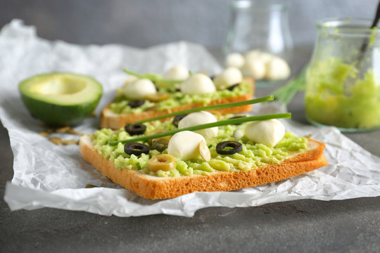 Tasty toast with avocado paste, cheese and olives on table, closeup