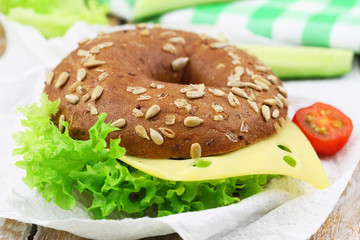 Brown bagel with cheese and lettuce, closeup
