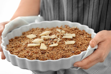 Woman holding baking dish with apple crisp, closeup