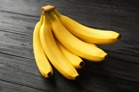 Tasty ripe bananas on dark wooden background