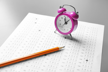 Fototapeta na wymiar Exam form, pencil and alarm clock on table