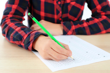 Student choosing answers in test form to pass exam at table