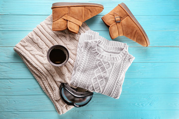 Warm clothes with ski goggles and cup of coffee on wooden background. Winter vacation concept
