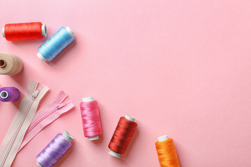 Set of sewing threads with zippers on color background, top view