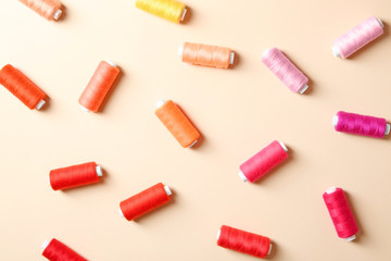 Set of sewing threads on color background, top view