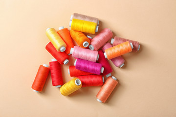 Set of sewing threads on color background, top view