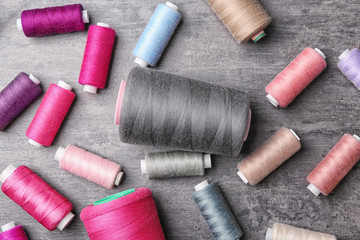 Set of color sewing threads on grey background, top view