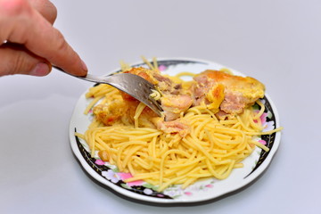 Veal strips with white mushrooms and onion in cream sauce served on fusilli pasta and garnished with a parsley leaf (Selective Focus, Focus on the parsley, the meat below and the front of the fork)
