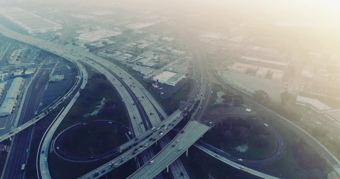 Above busy freeway intersection at sunset during rush hour traffic - aerial shot 