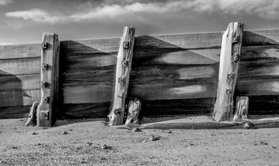 wooden, weathered sea groyne and metal bolts, gnarled planks of wood
