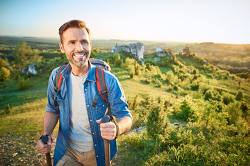 Smiling man hiking in the mountains using poles and looking away