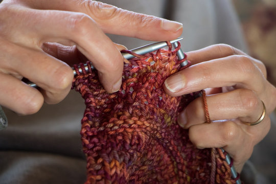 Woman knitting a red and orange scarf 