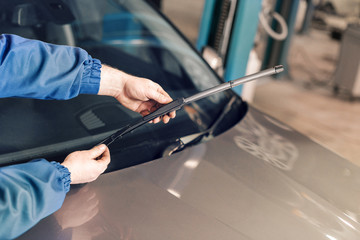Technician is changing windscreen wipers on a car station. - 188016205