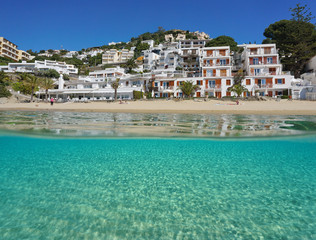 Mediterranean beachfront over and under sea surface with buildings and a sandy seabed underwater,...