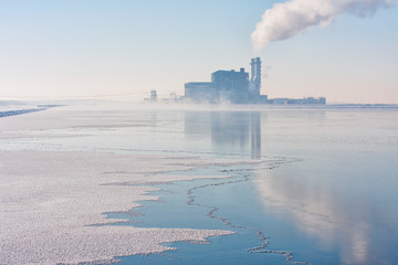 Dutch frozen lake covered with haze and view at a power plant