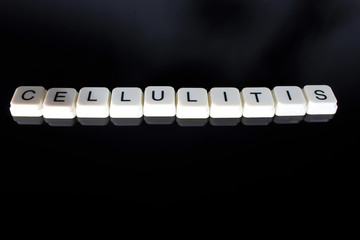 Cellulitis text word title caption label cover backdrop background. Alphabet letter toy blocks on black reflective background. White alphabetical letters. White educational toy block with words on