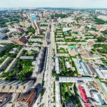 Aerial city view with crossroads and roads, houses, buildings, parks and parking lots, bridges. Helicopter drone shot. Wide Panoramic image.