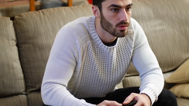 Young male sport supporter watching game at home on TV, celebrating his team winning