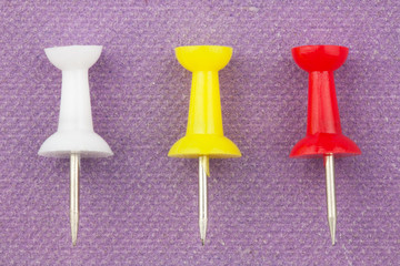 closeup of tree color buttons on the purple paper background. There are yellow, white and red buttons