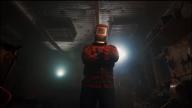 Portrait Of A Man With Crossed Arms In The Welding Mask In The Home Garage