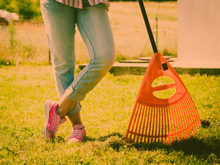 Woman using rake to clean up garden lawn