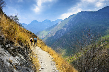Fototapeta na wymiar Hiking path (the high road) of Tiger Leaping Gorge. Travelers hiking in the mountains. Located 60 kilometres north of Lijiang City, Yunnan Province, China.