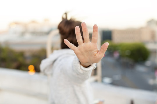 A girl signals with her hand that she is not wanting to talk or be bothered