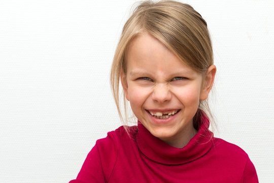 Portr&auml;t eines 6 Jahre alten blonden M&auml;dchens. Es tr&auml;gt einen roten Rollkragenpullover und hat ein strahlendes Lachen