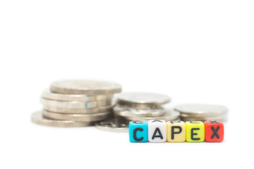 Close up image of the alphabet dices which are arranged for a word CAPEX, in front of stack of...