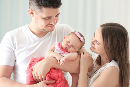 Happy young family holding cute sleeping newborn baby at home, closeup