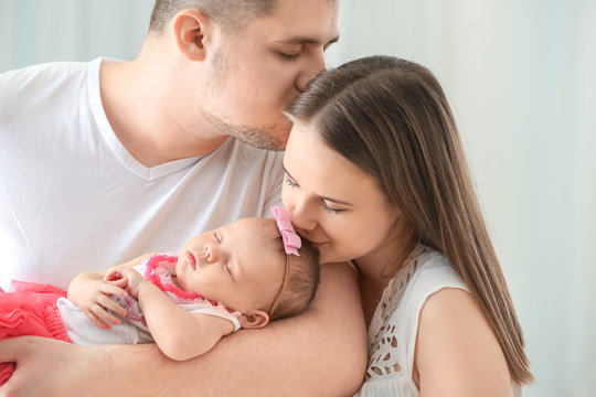 Happy young family with cute sleeping newborn baby at home, closeup