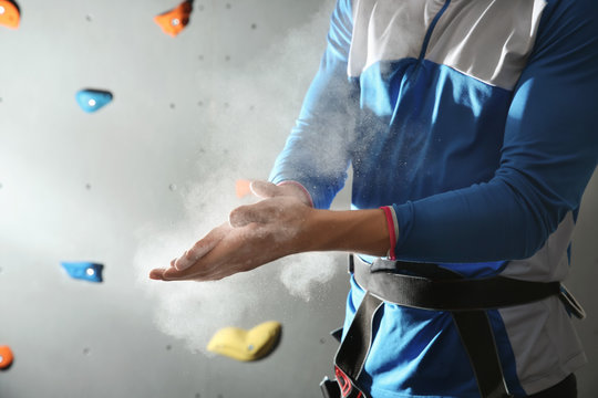 Young man applying talc powder on hands in climbing gym