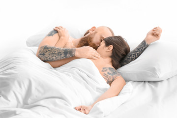 Attractive young couple with tattoos in bed at home