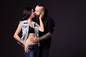Tattooed man kissing his girlfriend on dark background