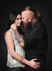 Tattooed man with his girlfriend on dark background