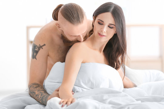 Tattooed man with his girlfriend in bed at home