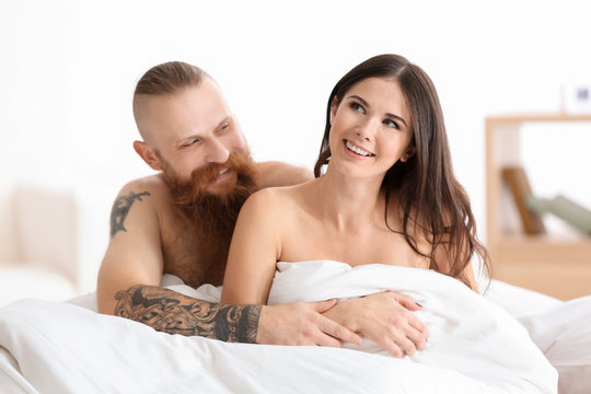 Tattooed man with his girlfriend in bed at home