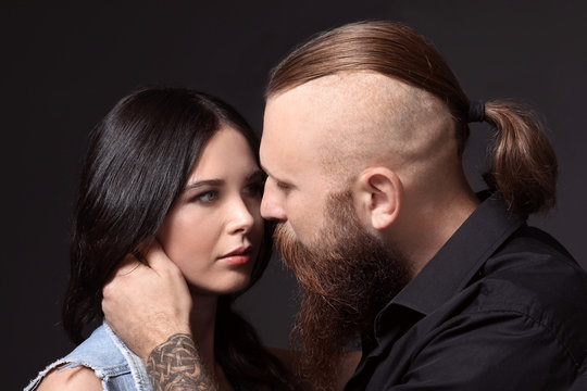 Tattooed man with his girlfriend on dark background
