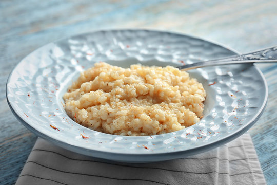 Dish with delicious risotto on wooden table
