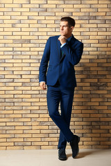 Handsome man in elegant suit near brick wall