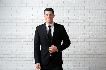 Handsome man in elegant suit near white brick wall