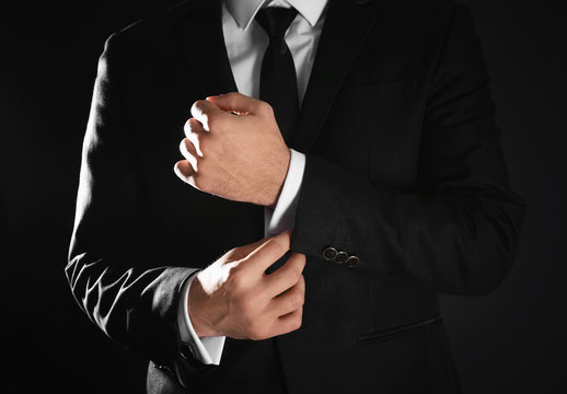 Handsome man in elegant suit on black background, closeup