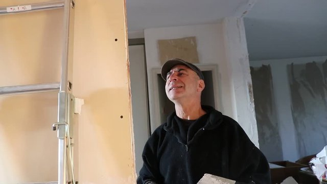 Handyman covers the holes in the wall with putty using a spatula in the work. Repair work in the house.