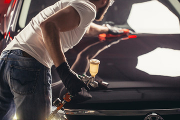 A man cleaning car with microfiber cloth, car detailing or valeting concept. Selective focus.